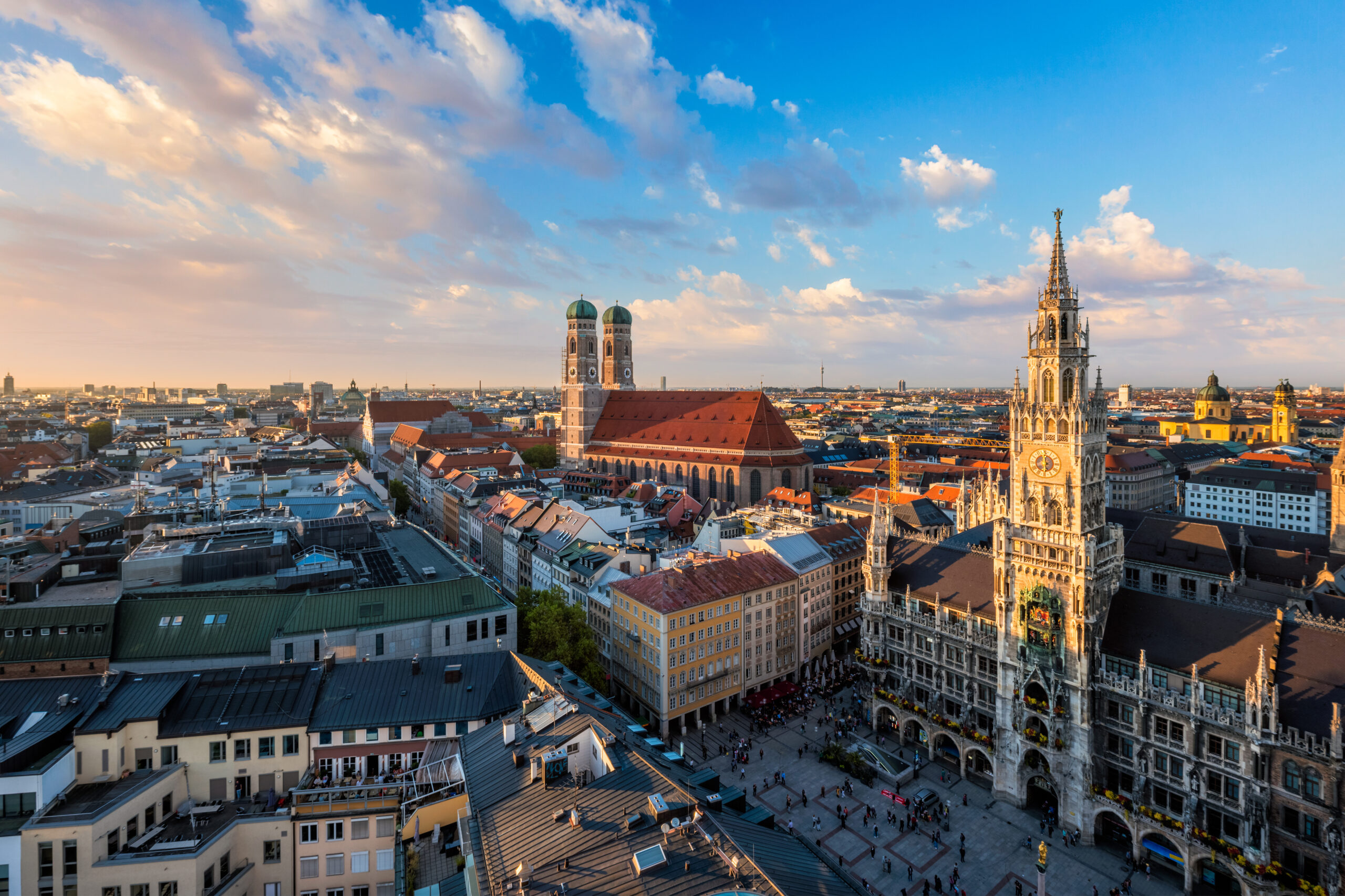 Blick von oben auf den Marienplatz in München mit Neuem Rathaus und Frauenkirche bei Sonnenuntergang.